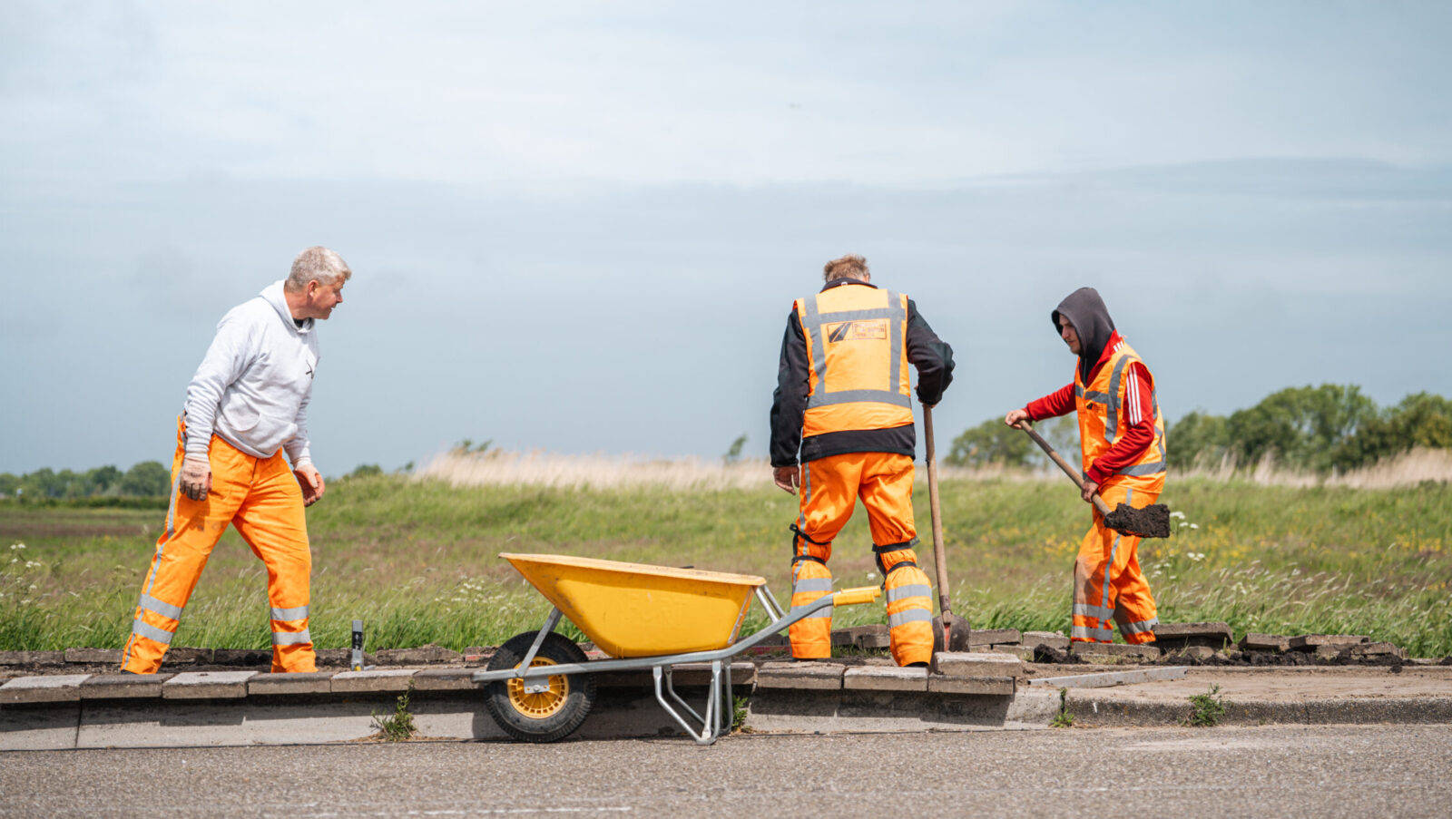 Opperman en stratenmaker werken samen aan de aanleg van bestrating.
