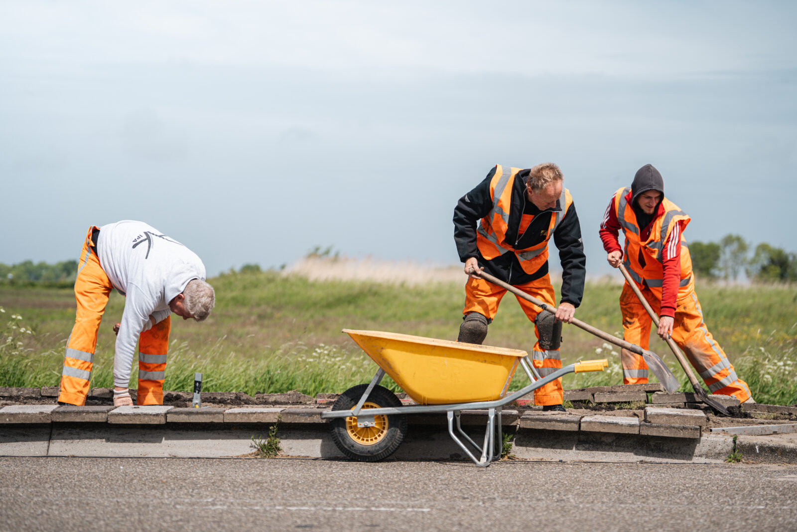 Drie medewerkers werken samen aan de aanleg van bestrating op locatie.