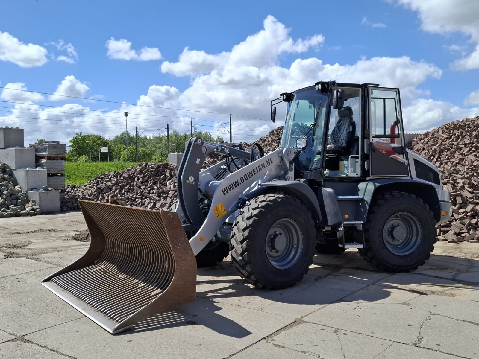 Shovelmachinist met shovel en zeefbak op een bestratingsdepot
